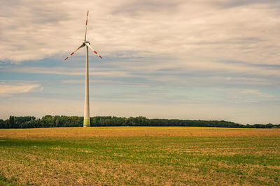 Wind turbines on field against sky