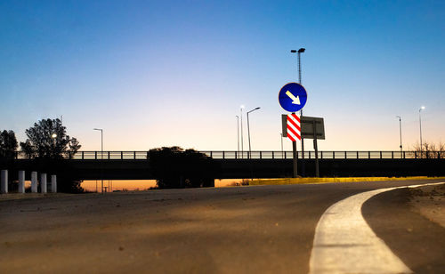 Road sign on street against clear blue sky