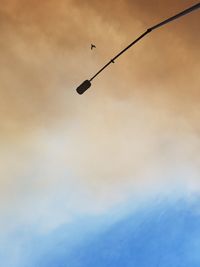 Low angle view of silhouette street light against cloudy sky during sunset