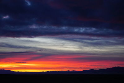 Scenic view of dramatic sky over silhouette landscape