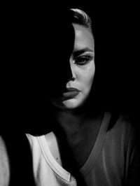 Close-up portrait of woman against black background