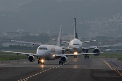 Airplane at airport runway against sky