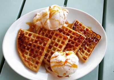 High angle view of waffles with honey and ice cream in plate on table