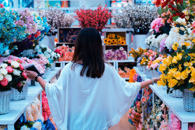 Rear view of woman amidst flowers in market