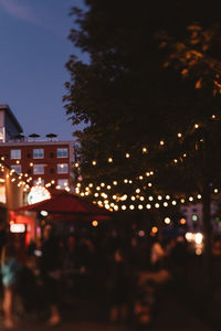 Defocused image of illuminated buildings against sky at night