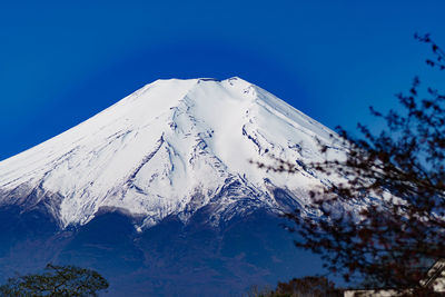 Low angle view of snowcapped mountain against clear blue sky