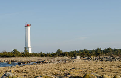 Lighthouse by street amidst buildings against sky