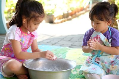 Cute girls playing with dough in container at back yard