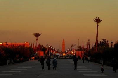 People in city against clear sky during sunset