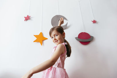 Portrait of smiling girl standing against wall