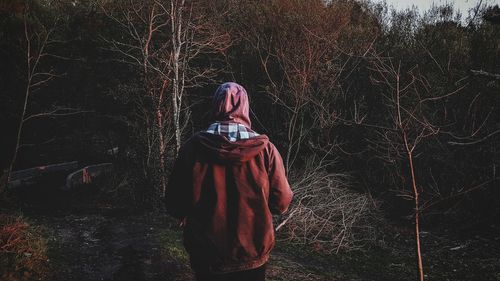 Woman standing by tree in forest