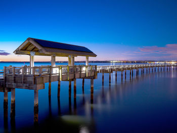 Pier on sea against clear blue sky at dusk