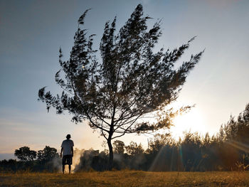 Rear view of man standing on field against sky