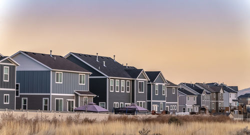 Houses on field against sky during sunset