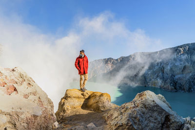 Full length of man standing on rock formation by lake