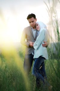 Couple standing on field against sky