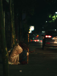 Man with umbrella on street in city at night