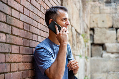 Young latin man talking by mobile phone outdoors