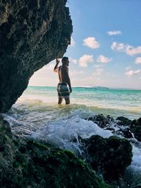 Shirtless man standing in sea against sky