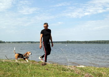 Portrait of man with dog standing on lake against sky