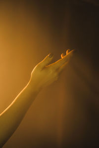 Close-up of hand holding illuminated light over colored background