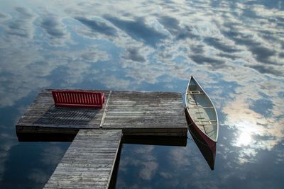 Canoe and red bench with reflected clouds in the water