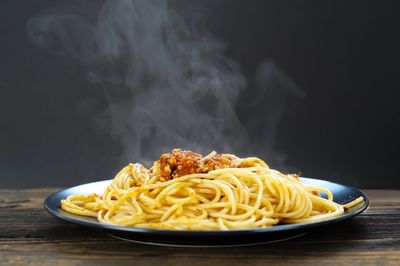 Close-up of noodles in plate on table against black background