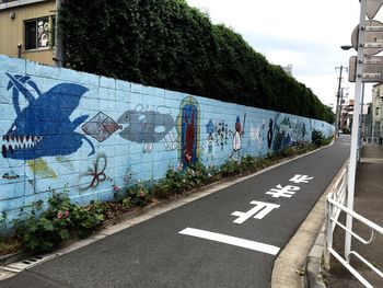 Graffiti on wall by road against sky