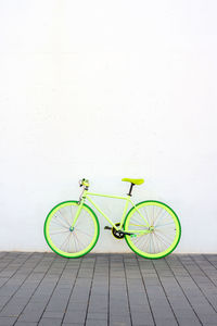 A green vintage city bicycle fixed gear on white wall