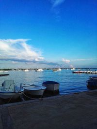 Sailboats moored in sea against blue sky