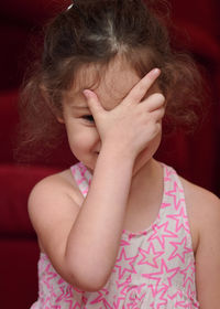 Portrait of a young girl in the livingroom at home making faces and signs of the camera