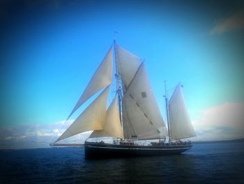 Sailboat sailing in sea against blue sky