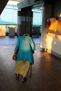 Rear view of senior woman walking at hallway