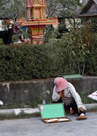 Market vendor with box sitting on footpath