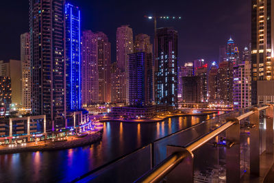 Illuminated buildings by river at night