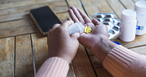 Cropped hands of woman with pills on table