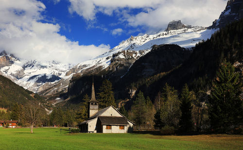 Church on field against snowy mountains