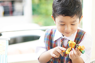 Cute boy holding toy while looking away