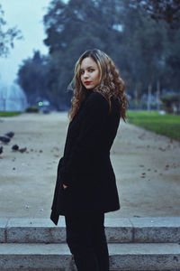 Young woman standing against tree