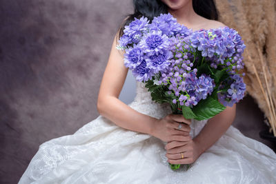 Midsection of woman holding purple flower
