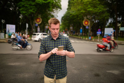 Man using mobile phone on road in city