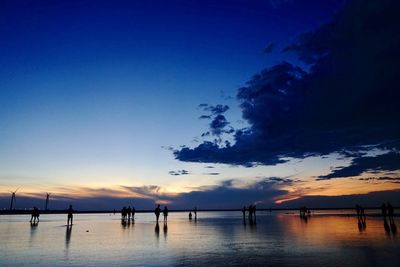 Silhouette people on beach against sky during sunset