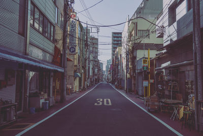 Empty road amidst buildings in city