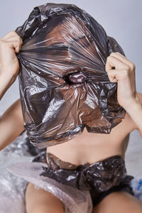 Young woman wearing plastic on face against white background