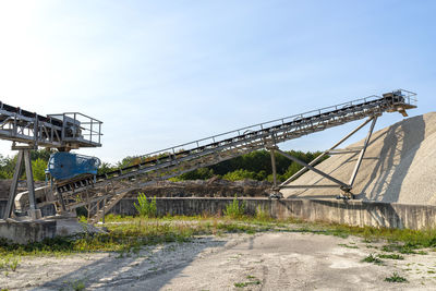 A system of interconnected conveyor belts over heaps of gravel  an industrial cement plant.