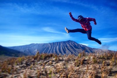 Man jumping in mountain against sky