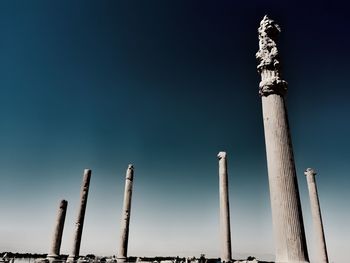 Low angle view of poles against clear blue sky