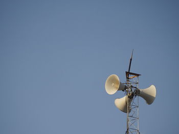 Low angle view of speakers against clear blue sky