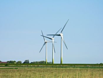 Wind turbines on field against clear sky