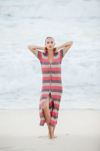 Full length portrait of young woman standing at beach